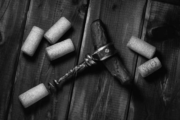 木製の背景にコルクねじとワインコルク 白黒写真 — ストック写真