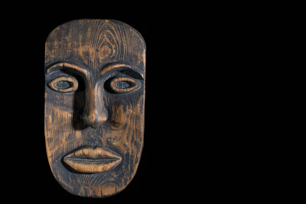 African mask carved from wood on a black background. Free space, black background