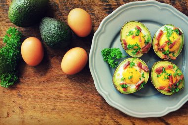 Avokado yumurta tekneler ahşap masa üzerinde pastırmalı. Üstten Görünüm.