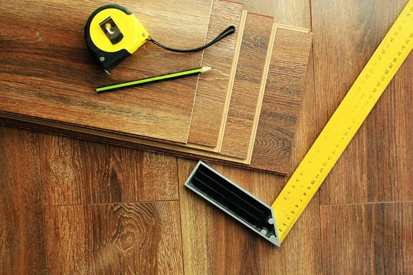 Laminátová podlaha prkna a nástroje na dřevěné pozadí. Pohled shora. — Stock fotografie