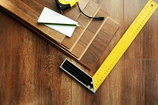 Laminate floor planks and tools on wooden background. Top view. — Stock Photo, Image