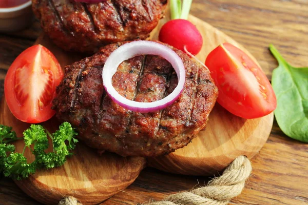 Hambúrguer de carne caseiro com cebola na tábua de corte — Fotografia de Stock