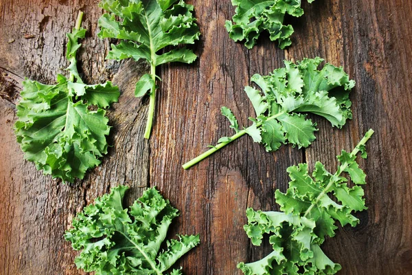 Hoja fresca de col rizada sobre fondo de madera. Hojas de verduras verdes. Vista superior. Alimentación saludable, comida vegetariana —  Fotos de Stock