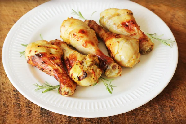 Ahşap masa rosemary ile beyaz tabakta üzerine hardallı tavuk budu ızgara. Barbekü akşam yemeği arka plan — Stok fotoğraf