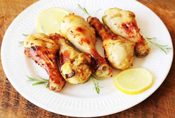 Ahşap masa beyaz biberiye ve limon ile tabakta üzerine hardallı tavuk budu ızgara. Barbekü akşam yemeği arka plan