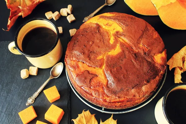 Pastel de chocolate con calabaza sobre fondo oscuro con hojas de otoño, vista superior — Foto de Stock