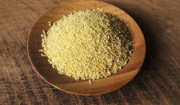 Kuru bulgur buğday ahşap kase izole Spilled bulgur