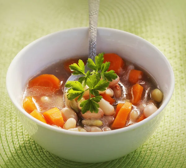 Zöldség leves bab és sárgarépa, zöld háttér — Stock Fotó