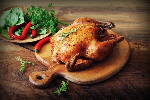 Whole roasted chicken on cutting board. Wooden rustic background — Stock Photo, Image