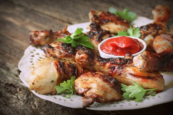 Grillade kycklingklubbor på träbord som serveras på vit platta med koriander — Stockfoto