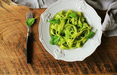 Tagliatelle makarna ıspanak ve ahşap arka plan üzerinde basilpesto. Üstten Görünüm