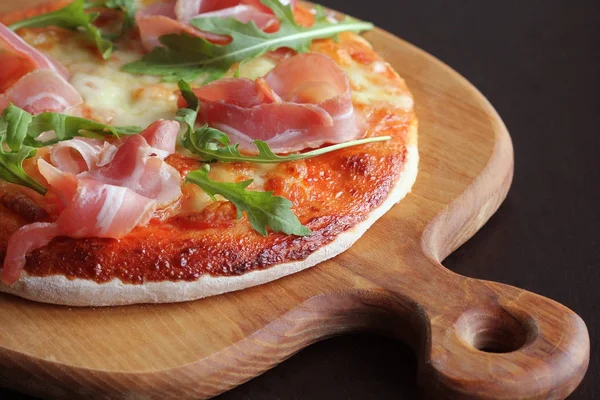 Jambon füme ve rucola koyu arka plan üzerinde pizza