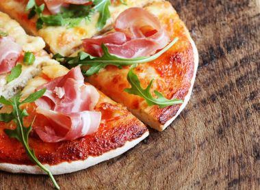 Jambon füme ve rucola ahşap arka plan üzerinde pizza