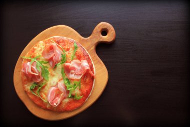 Jambon füme ve rucola koyu arka plan üzerinde pizza