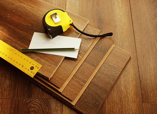 Laminatdielen und Werkzeuge auf Holzgrund. verschiedene Tischlerwerkzeuge auf dem Laminatboden. — Stockfoto