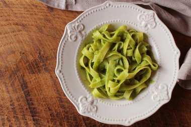 Tagliatelle makarna ıspanak ve ahşap arka plan üzerinde basilpesto. Üstten Görünüm