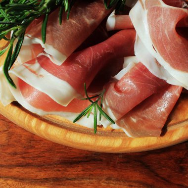 Kesme tahtası üzerinde biberiye ile İtalyan prosciutto crudo veya jamon