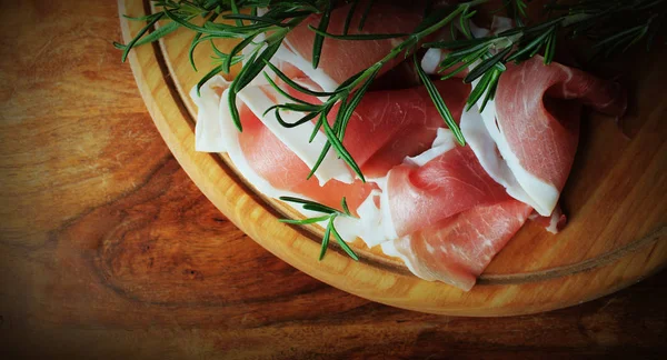 Italian prosciutto crudo or jamon with rosemary on cutting board — Stock Photo, Image
