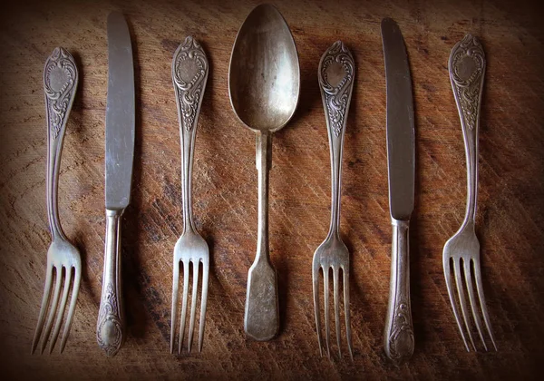 Spoon, forks, knives, ladles on a wooden table, selective focus and toned image. Top view — Stock Photo, Image