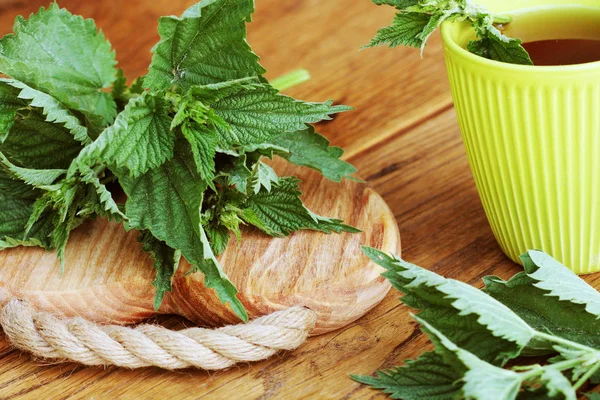 Stinging nettle on a cutting board and tea cup — Stock Photo, Image