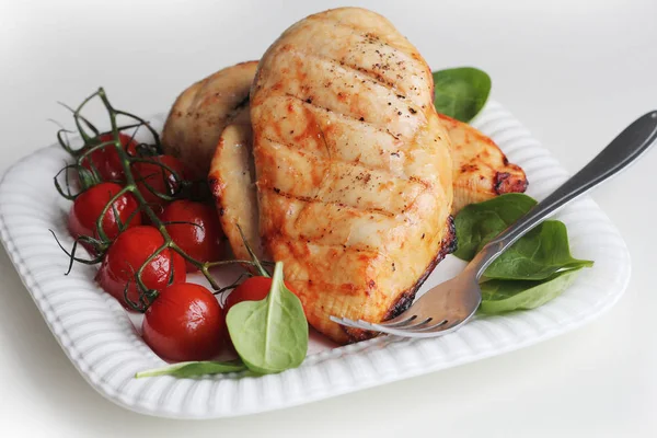 Peito de frango grelhado com tomate cereja, espinafre em uma placa branca — Fotografia de Stock