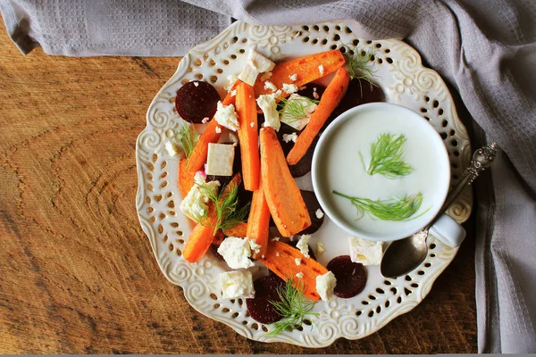 Здоровий смажена буряк, морква з сиром Фета, кріп і грецький йогурт в невелику скляну салатниці на сільському дерев'яний стіл, вид зверху — стокове фото