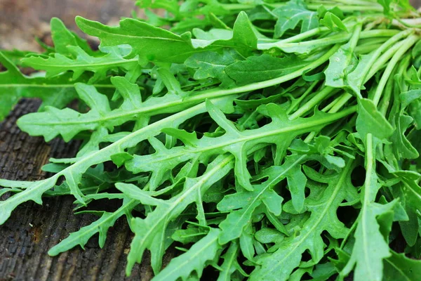 Folhas de arugula verdes frescas no fundo rústico de madeira. Salada de foguete ou rucola, comida saudável, dieta. Conceito de nutrição — Fotografia de Stock