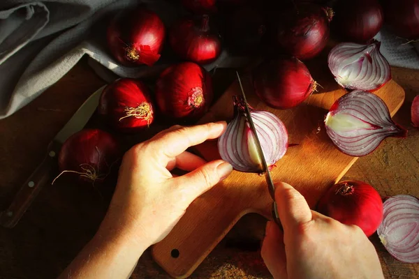 Dělení červené cibule s nožem na prkénku — Stock fotografie