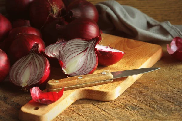 Rode uien op hout snijden snijplank over donkere houten rustieke textuur achtergrond. Bovenaanzicht, ruimte voor tekst — Stockfoto