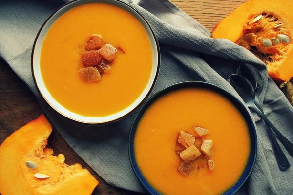 Soupe de citrouille avec croûtes, servie dans un bol noir et blanc. Vue du dessus, arrière-plan rustique — Photo