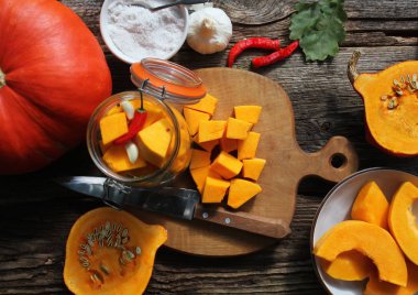 Bardakta taze ev yapımı balkabağı turşusu ve ahşap bir masada otlar. Üst görünüm