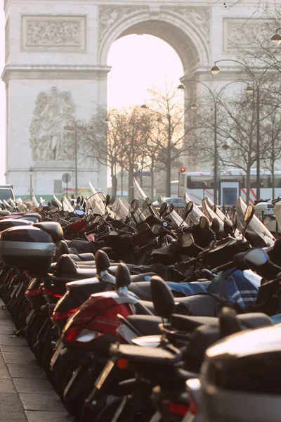 Motorcycles standing at the Parking lot. In the background are the motorcycles and Arch Triumph in Paris, France.
