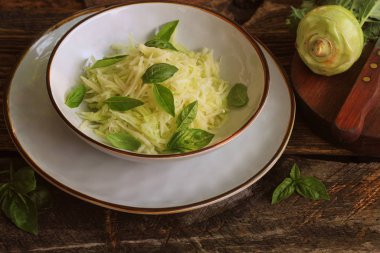 Kohlrabi, parmesan, fesleğen ve susam bir kase içinde dresing ile taze salata. Vejetaryen yemekler