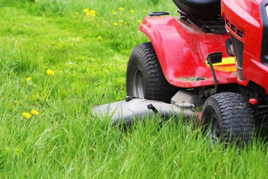 Bahçıvanlık konsepti. Bahçıvan traktör çim biçme makinesinin uzun çimlerini kesiyor. .