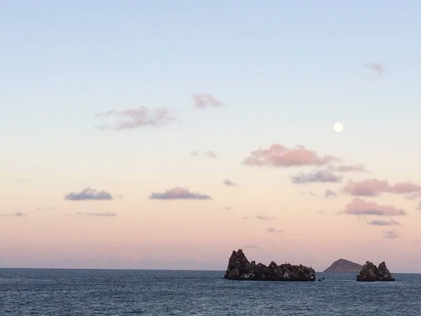 Galapagos sunset in the middle of the ocean with the moon up in the sky