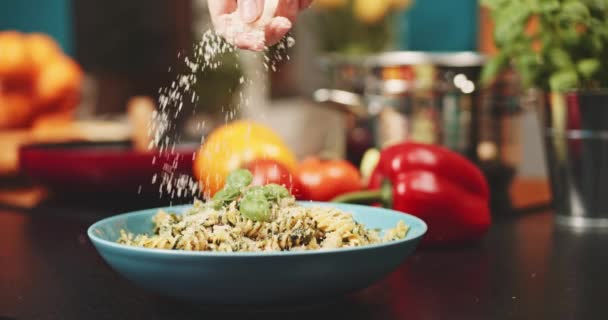 Colocando queijo parmesão em massas câmera lenta dolly tiro mãos mulher cobrindo fusilli macarrão com queijo italiano no fundo da cozinha deliciosa comida caseira cozinhar alimentação saudável — Vídeo de Stock