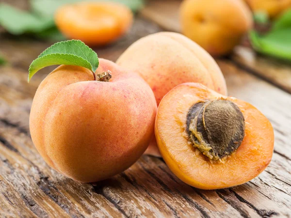 Apricots and its cross-section on the old wooden table. — Stock Photo, Image