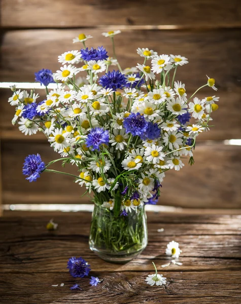 Kytice chamomiles a chrpy v váza na dřevěným — Stock fotografie