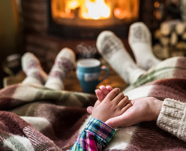 Oteplování a relaxaci u krbu. Matka a dcera drží — Stock fotografie