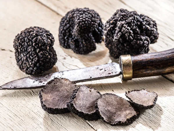 Trufas pretas na velha mesa de madeira. — Fotografia de Stock