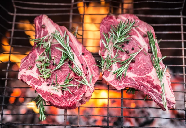 Filetes de costilla y parrilla con fuego ardiente detrás de ellos . — Foto de Stock