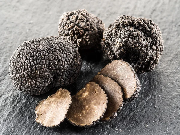 Black truffles and truffle slices on the graphite board. — Stock Photo, Image