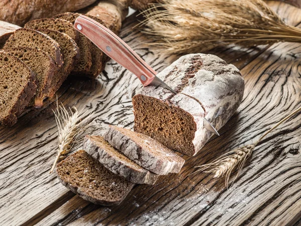 Pão preto fatiado na prancha de madeira . — Fotografia de Stock