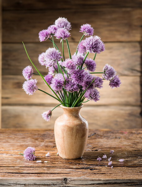 Bouquet of onion (chives) flowers in the vase on the wooden tabl