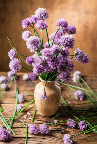 Bouquet of onion (chives) flowers in the vase on the wooden tabl Royalty Free Stock Photos