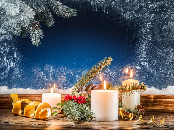 Cristmas candle lights and frozen window. Christmas background. — Stock Photo, Image