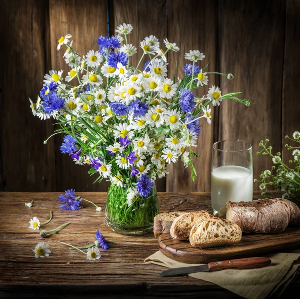 Buquê de flores de campo, copo de leite e pão macio no wo — Fotografia de Stock