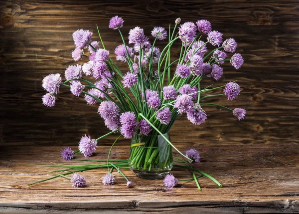 Bouquet di fiori di cipolla (erba cipollina) nel vaso sulla tavola di legno — Foto Stock