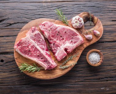 Ahşap kesme tahtası üzerinde baharatlar ile T-bone biftek.
