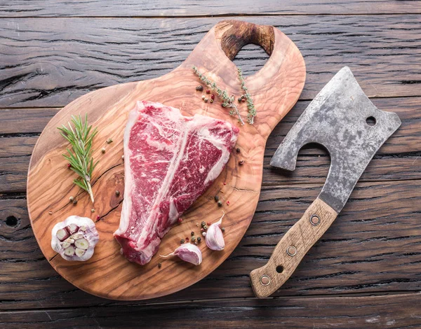 Ahşap kesme tahtası üzerinde baharatlar ile T-bone biftek. — Stok fotoğraf